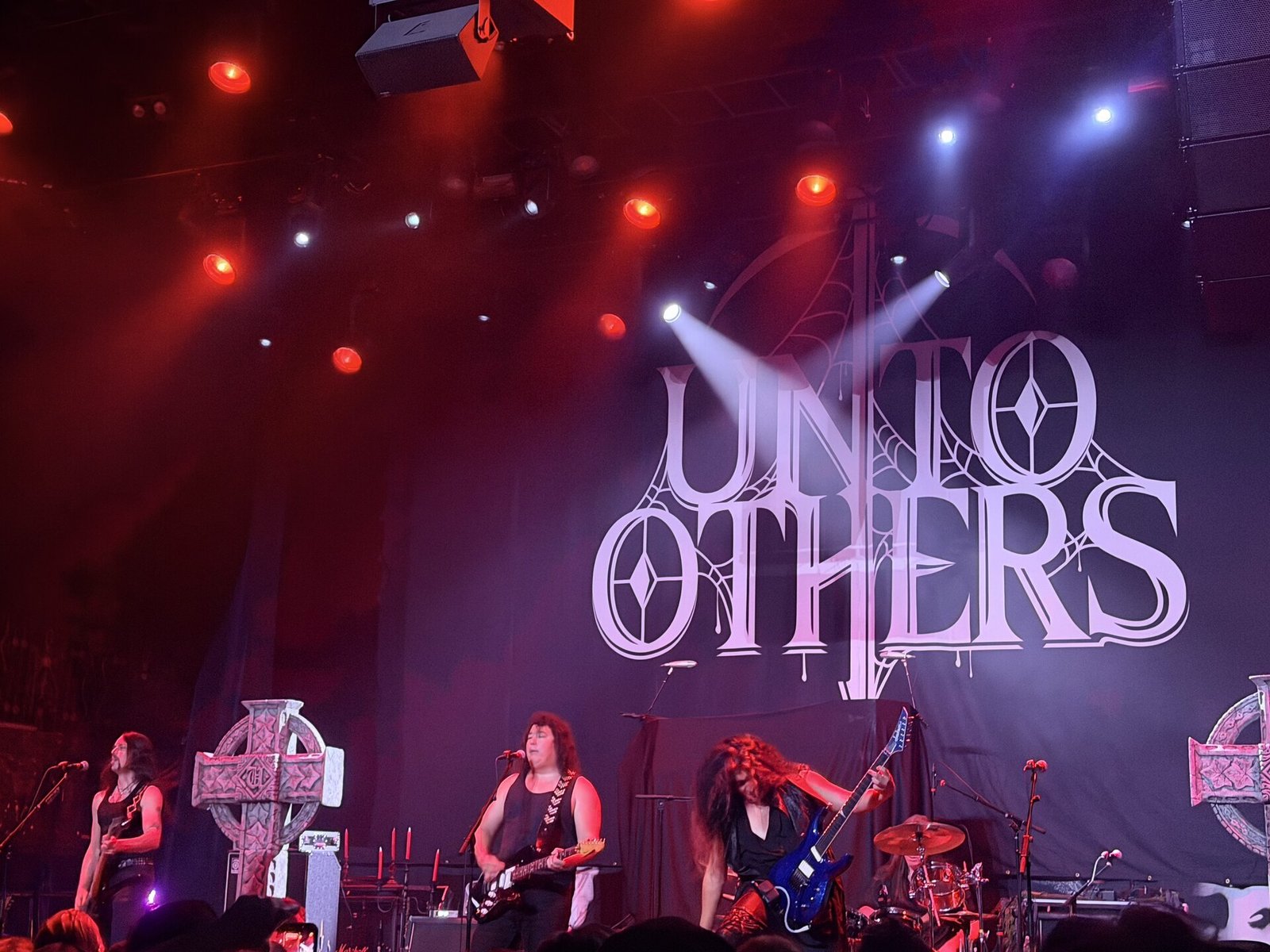 Unto Others live in front of their logo backdrop at Belasco Theater, Los Angeles, October 1, 2026